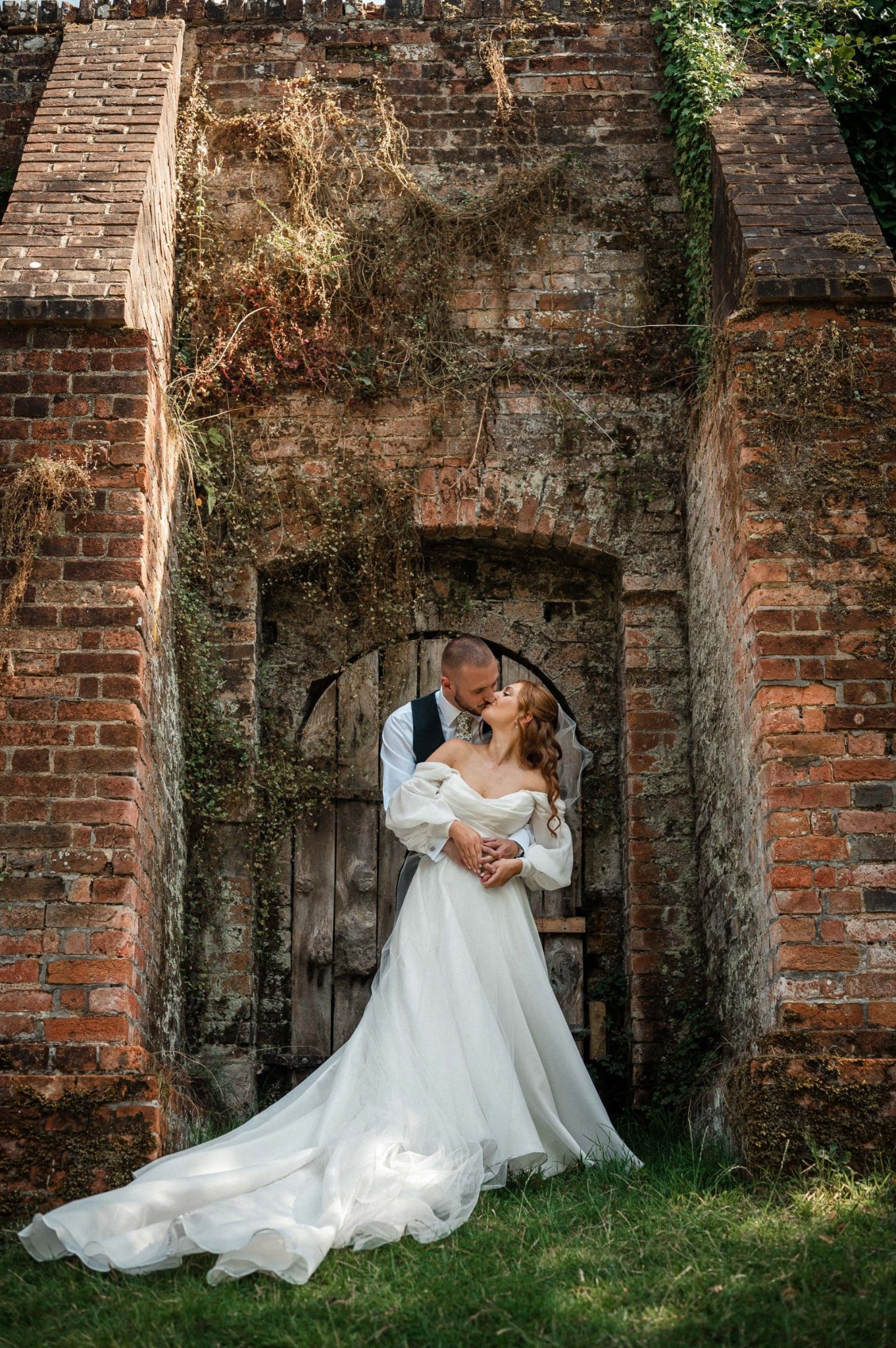 Bride and groom posed beneath old brick arches