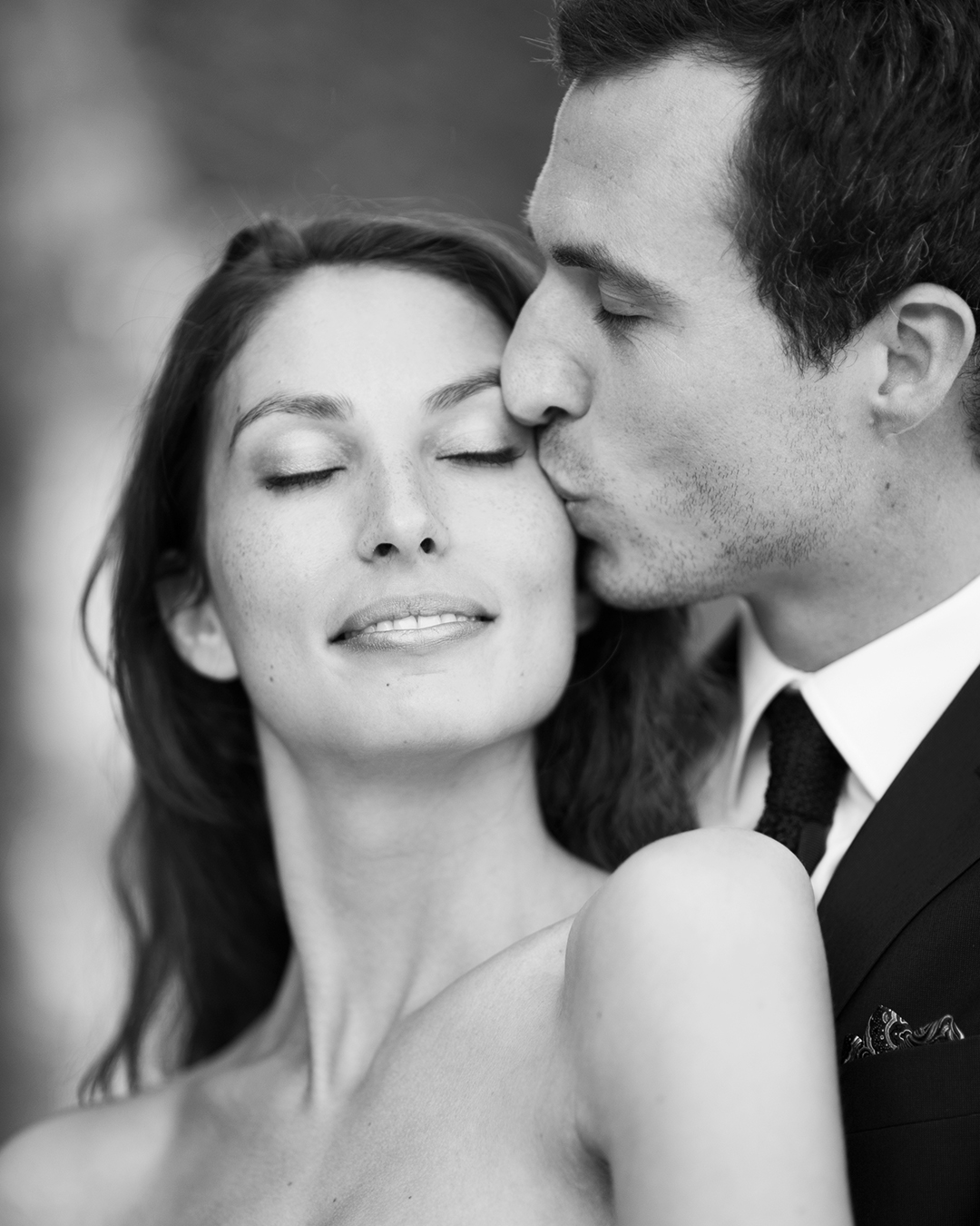 Black and white close portrait of a groom kissing the bride