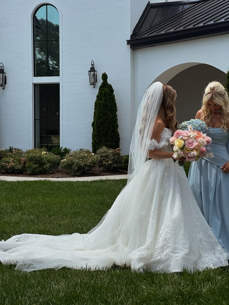 Bride with bridesmaid and pastel wedding bouquet outside a modern venue