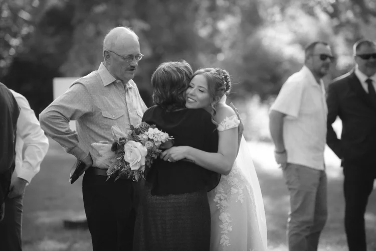 Bride embracing family member outdoors