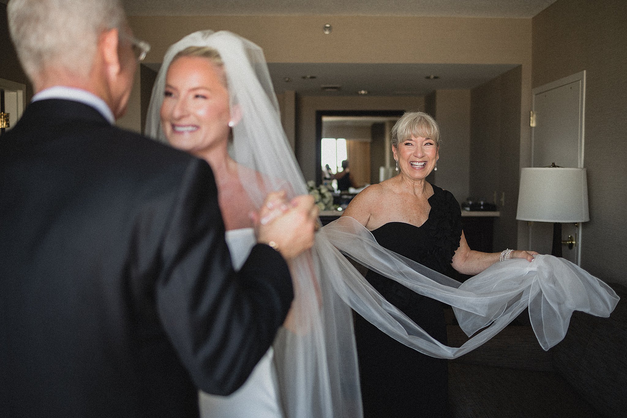 Mother of the bride holding the veil during a candid wedding morning moment