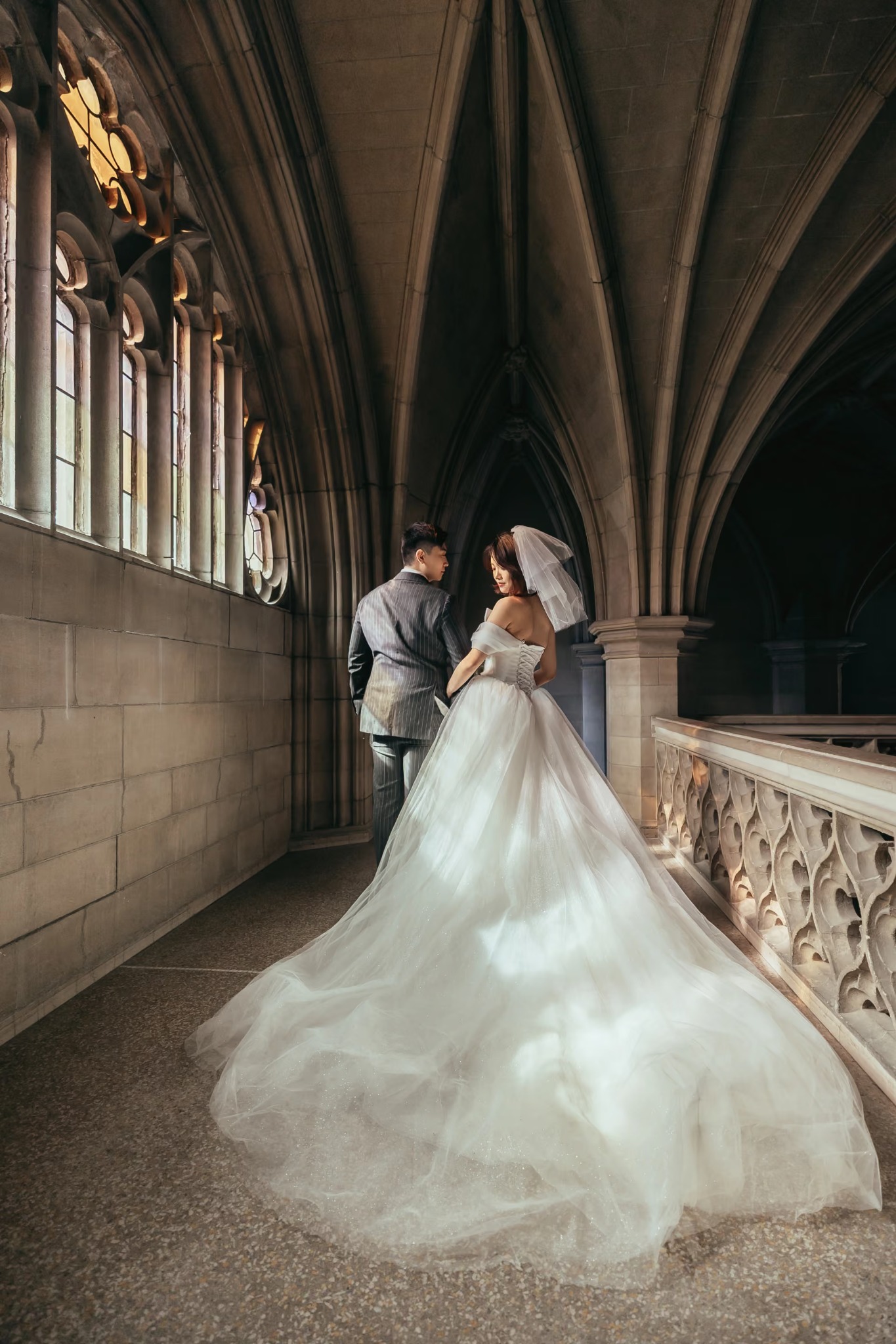 Bride and groom posing beneath elegant cathedral arches