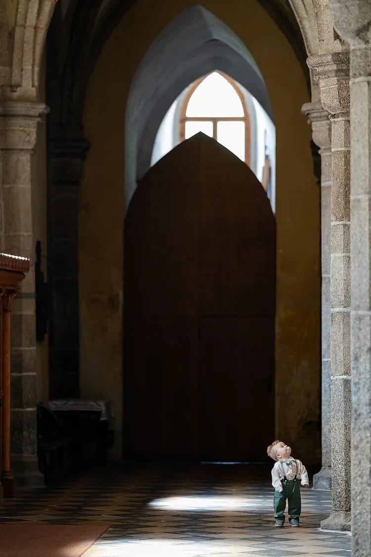 Young wedding guest standing in a beam of light inside a historic church