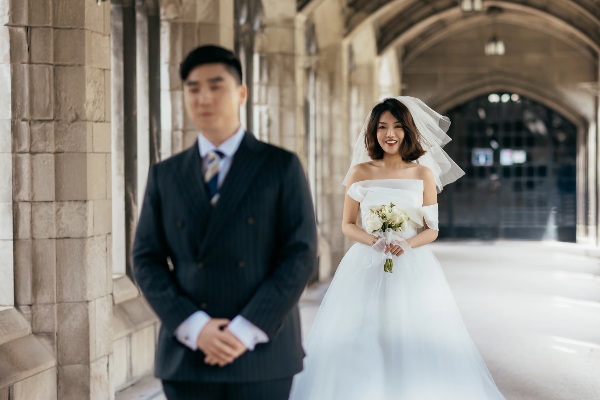 Bride approaching the groom beneath stone arches before the ceremony
