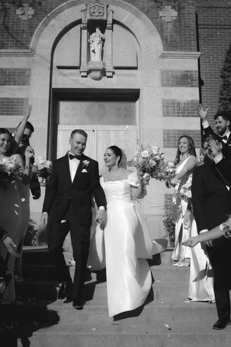 Newlyweds leaving the church surrounded by their wedding party