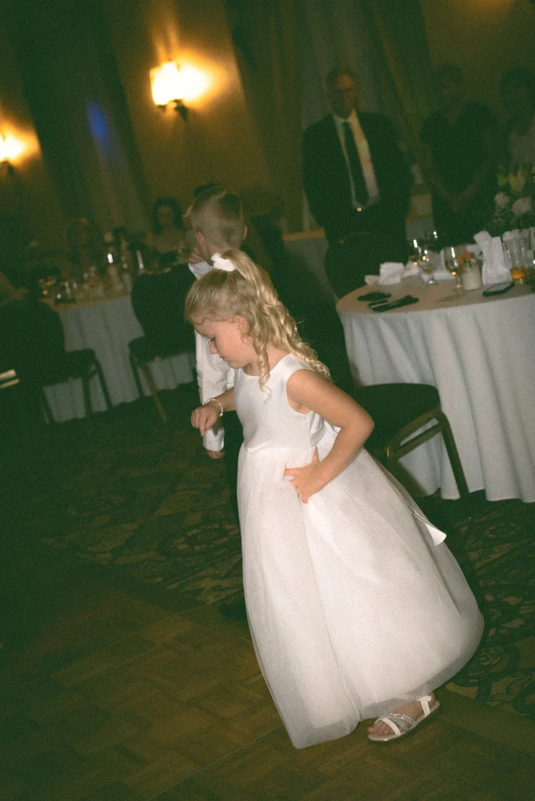 Young flower girl dancing at the wedding reception