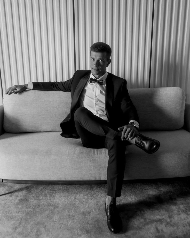 Editorial black and white portrait of a groom seated before the wedding