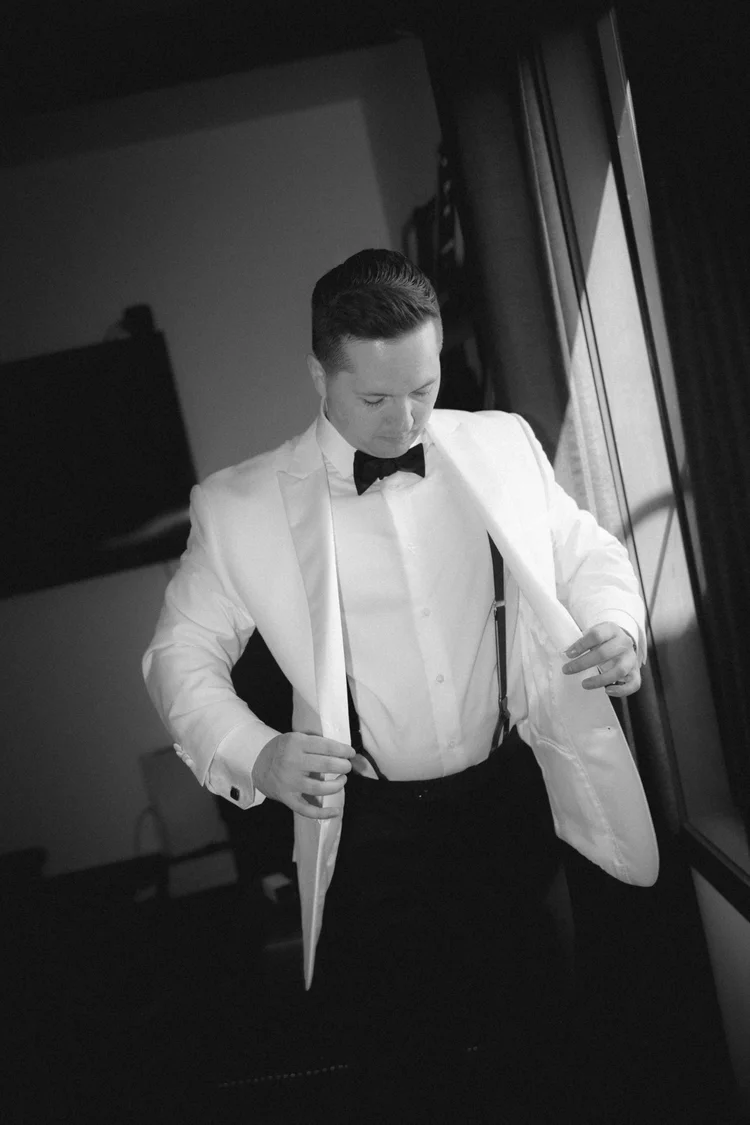 Groom in white tuxedo getting ready