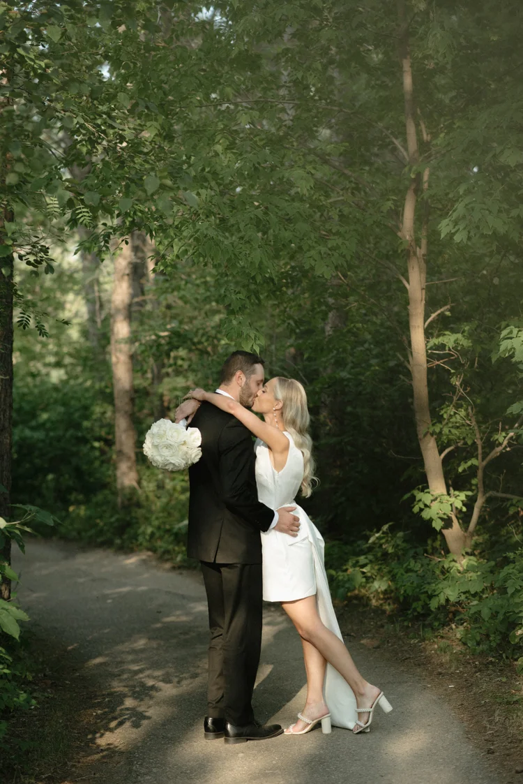Newlyweds kissing on a woodland path
