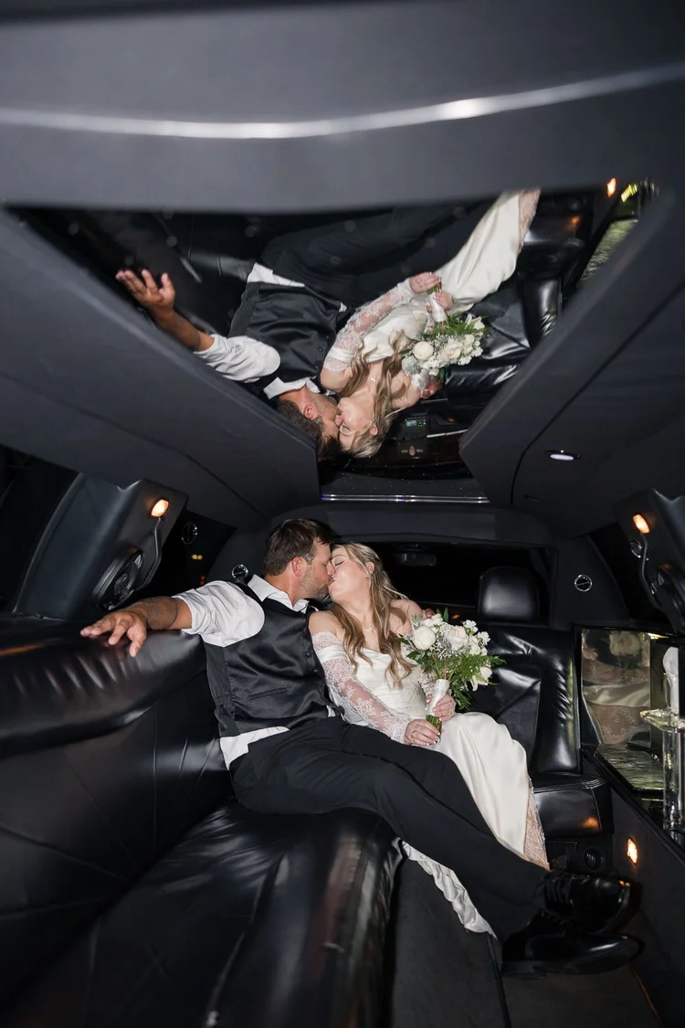 Newlyweds kissing inside a limousine after their wedding