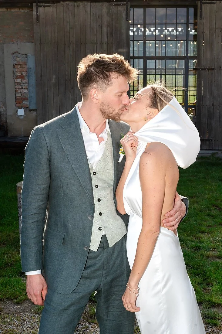Newlyweds kissing outdoors in bright evening sunlight