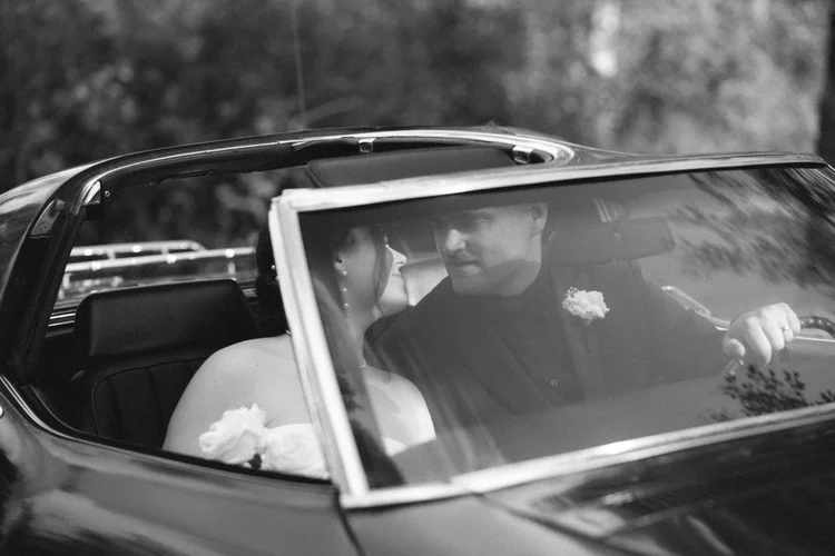 Bride and groom sharing a quiet moment inside a vintage car