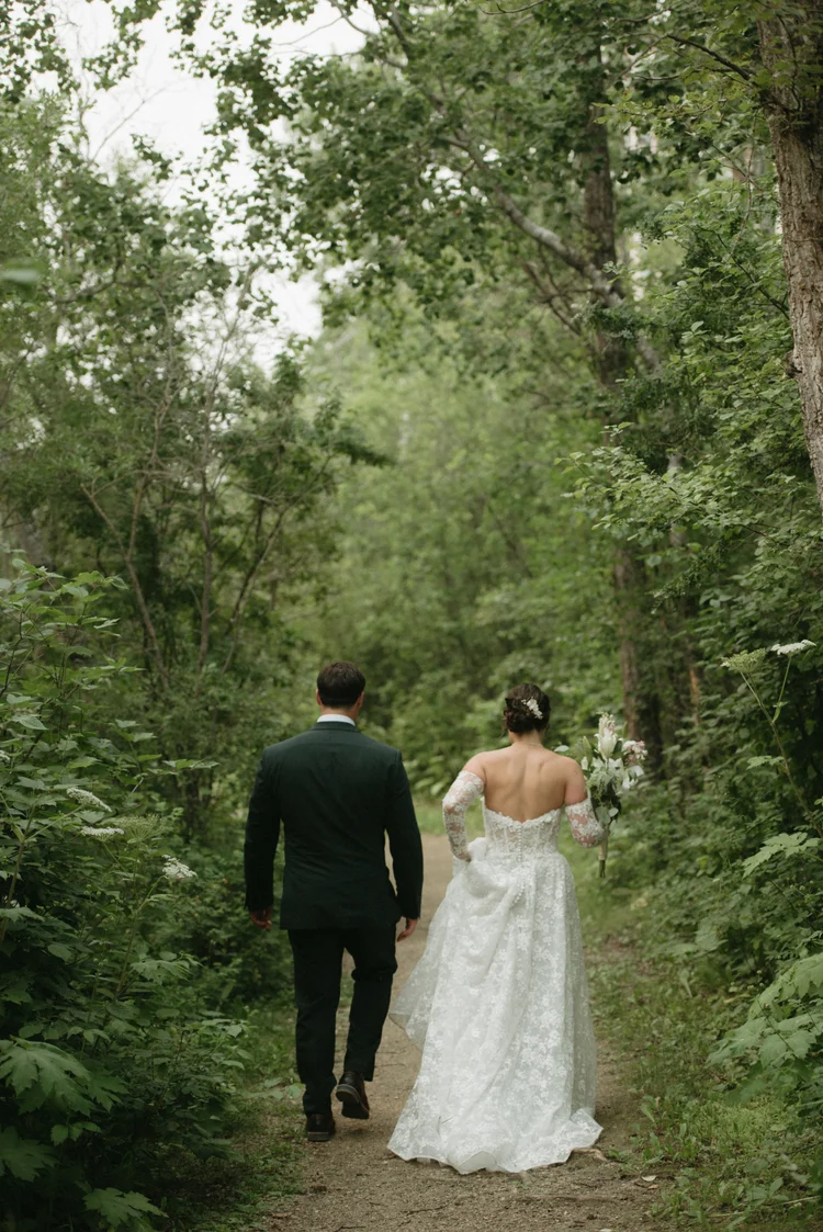 Newlyweds walking through a woodland trail