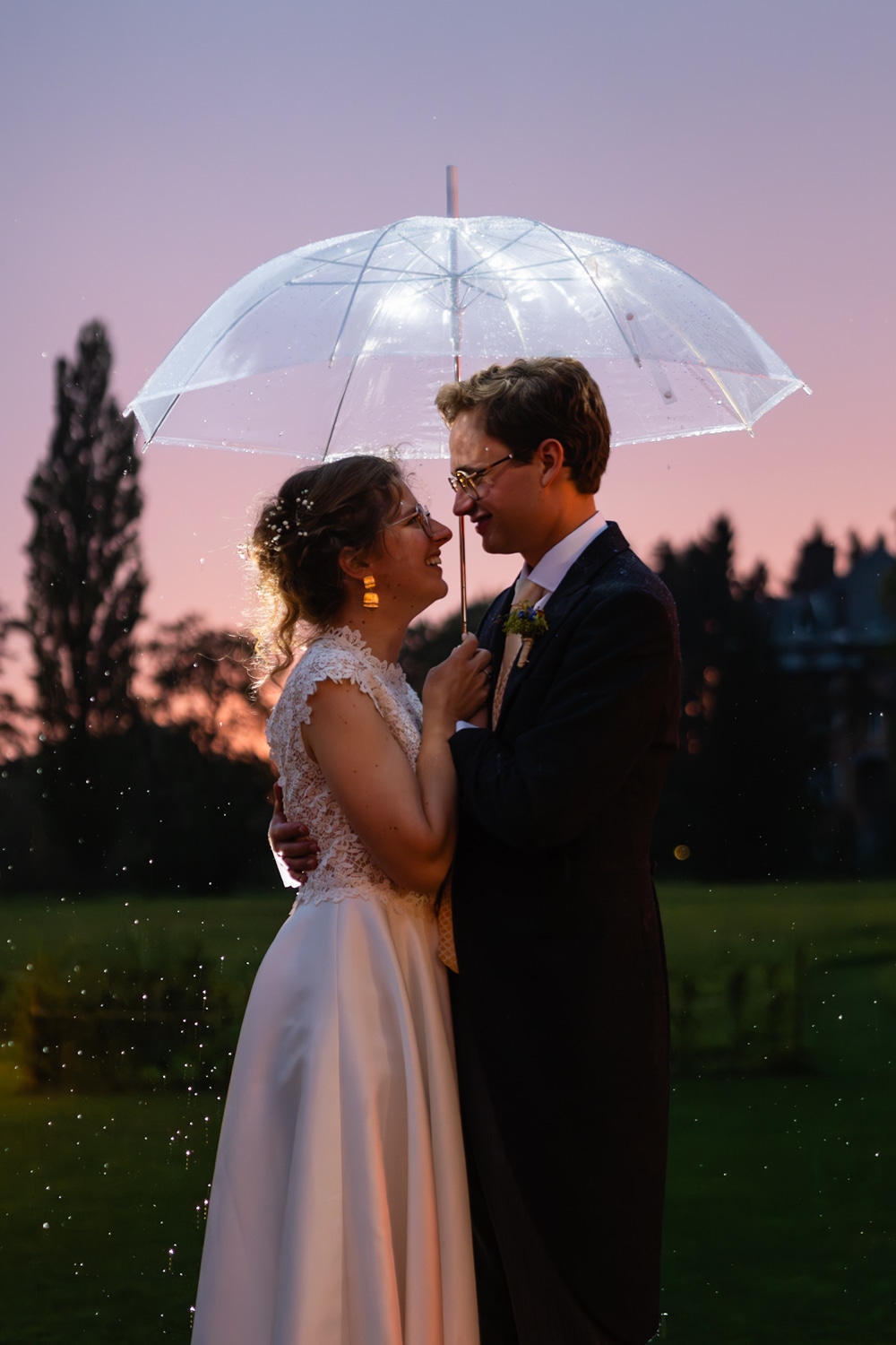 Bride and groom under an umbrella at sunset